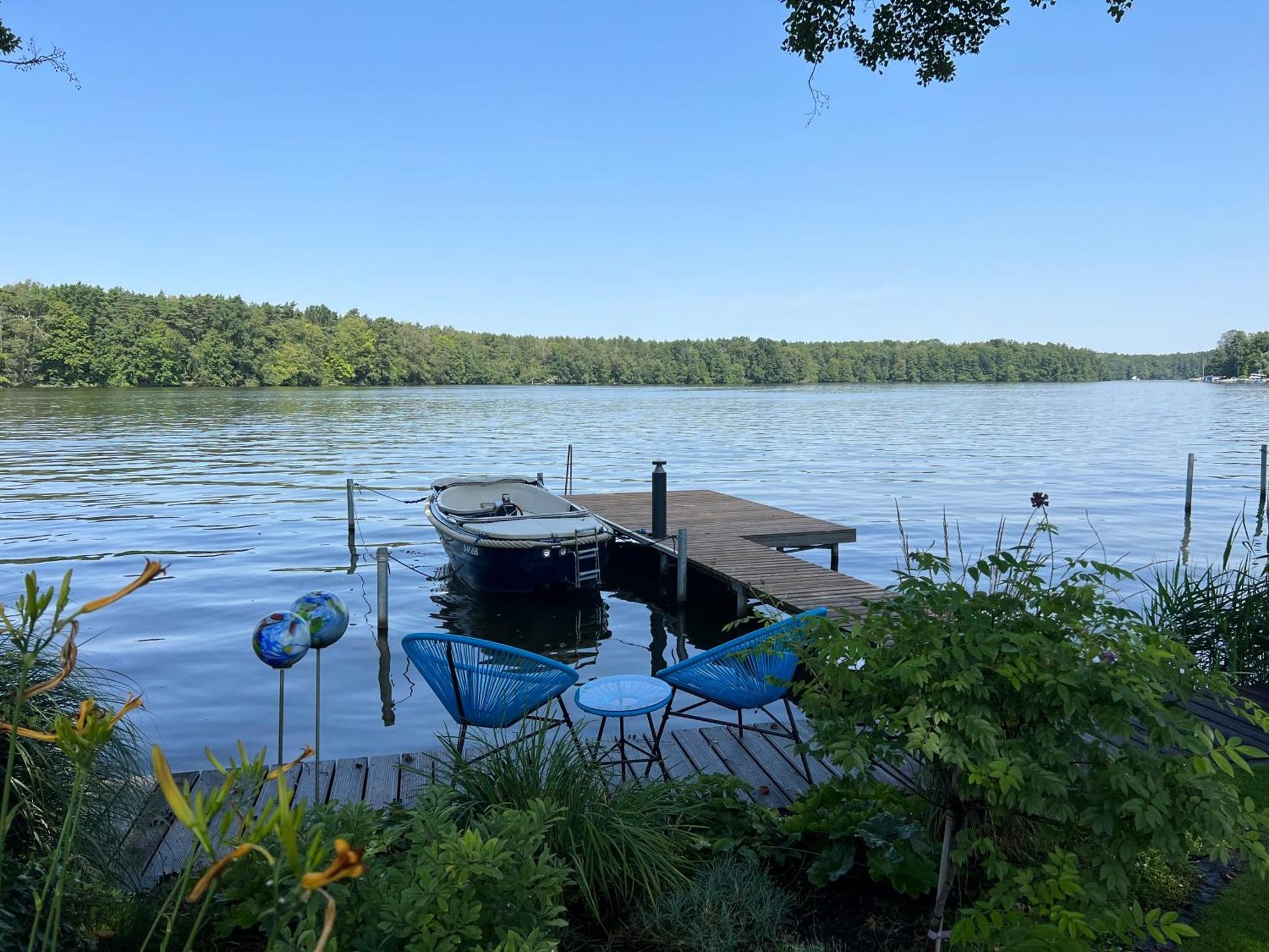 Steg am Großen Zug mit Motorboot und zwei blauen Stühlen, Blick über den See
