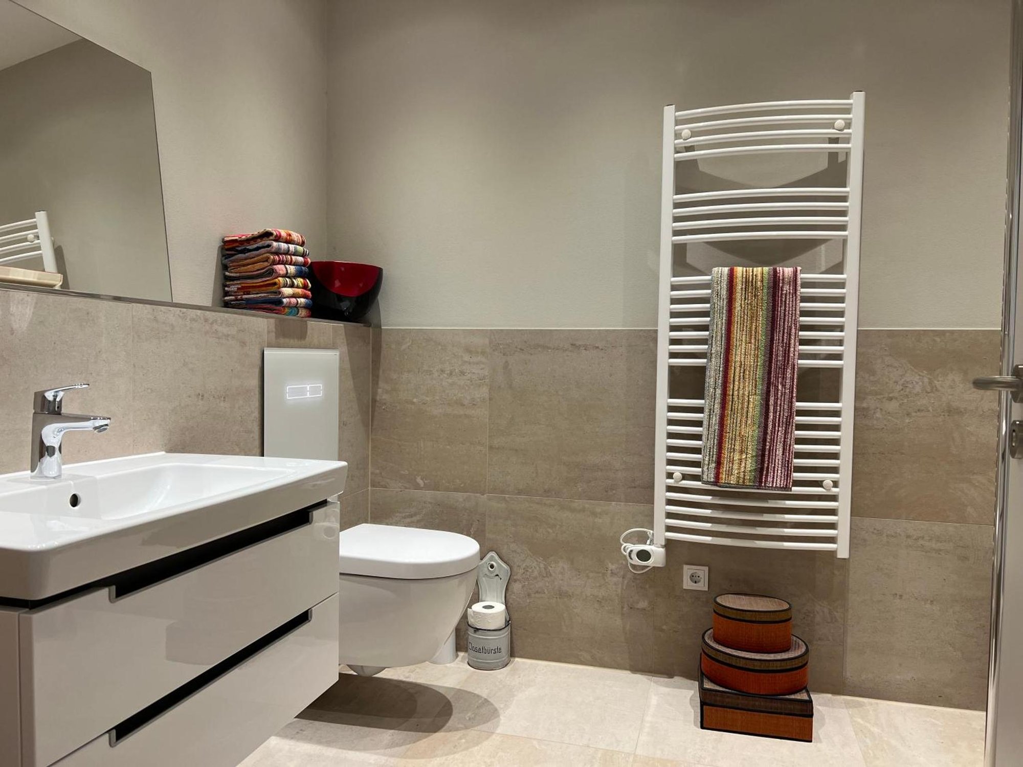 Bad des Gästehauses mit Waschtisch, WC und Handtuchheizkörper, beige Fliesen