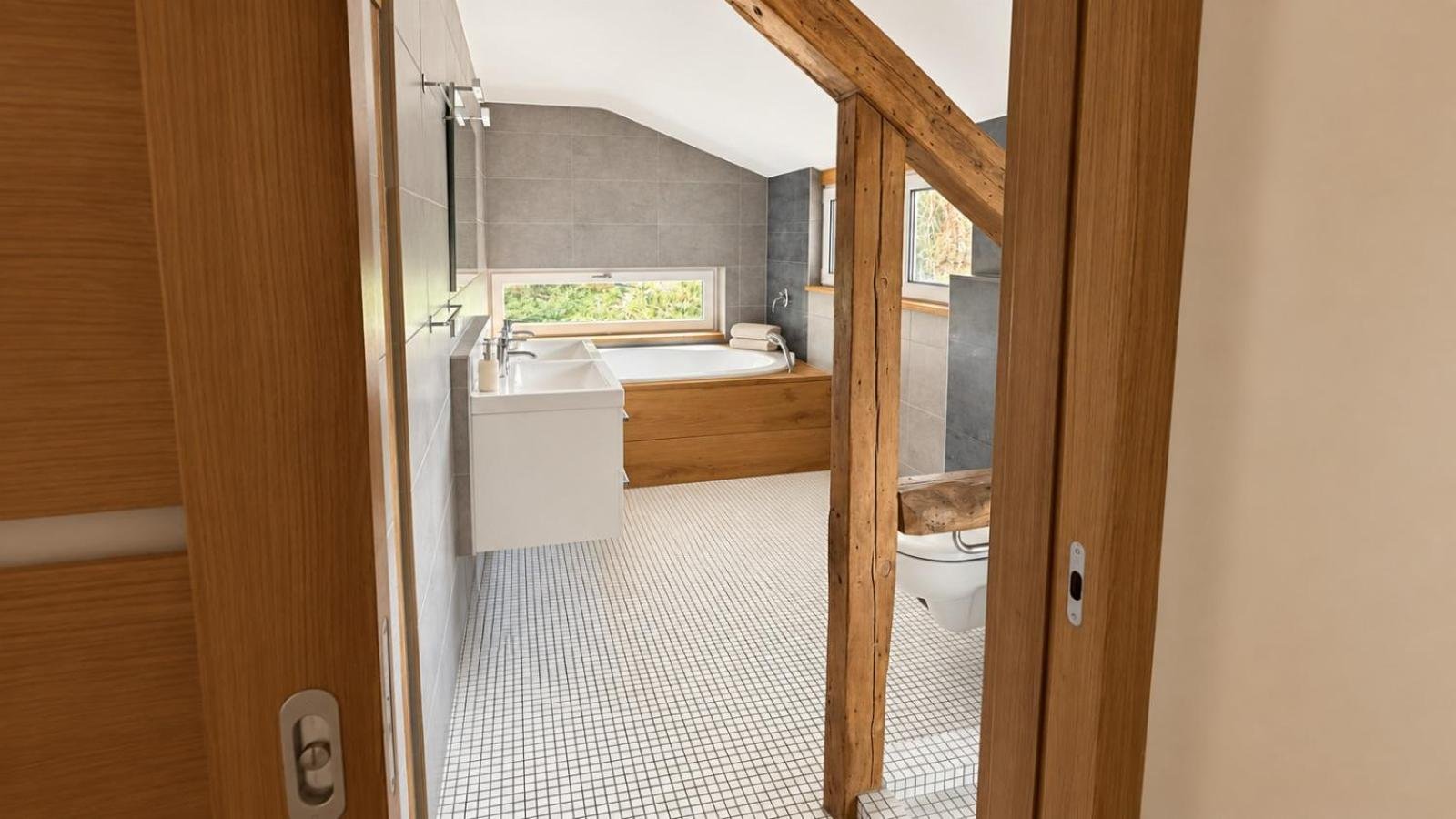 Bad mit Badewanne unter der Dachschräge, Holzbalken und Fenster