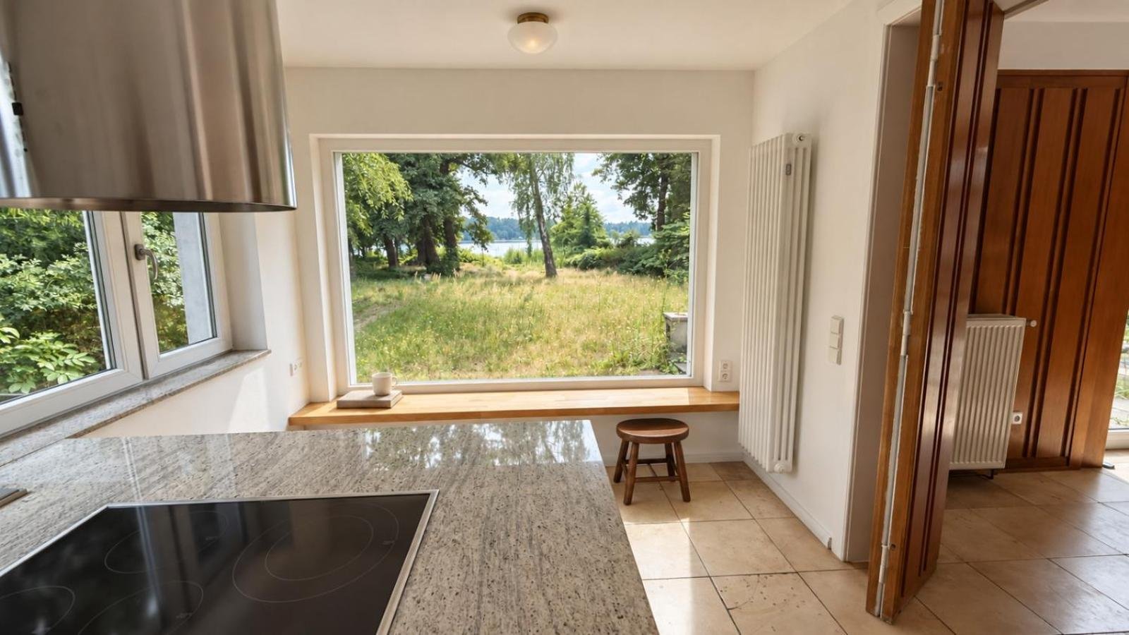 Küche mit Kochfeld auf der Insel, Dunstabzug und Fenster mit Seeblick